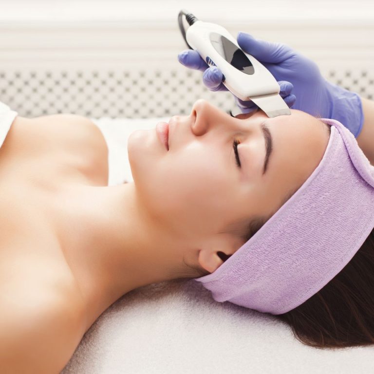 Rejuvenating facial treatment. Model getting lifting therapy massage in a beauty SPA salon. Exfoliation, stimulation and hydratation. Aesthetic cosmetology, closeup, copy space